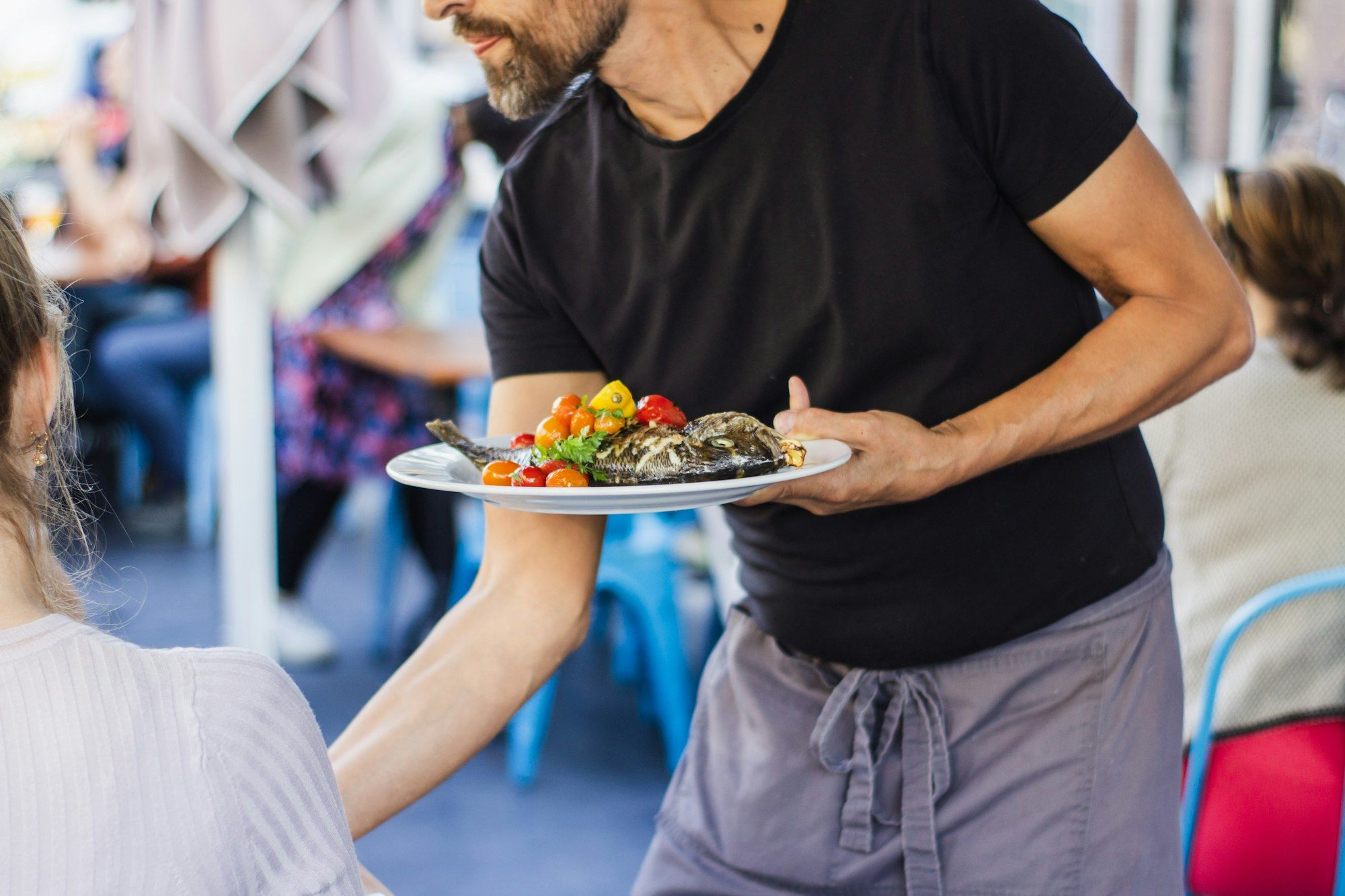 A server carrying plates through a busy restaurant